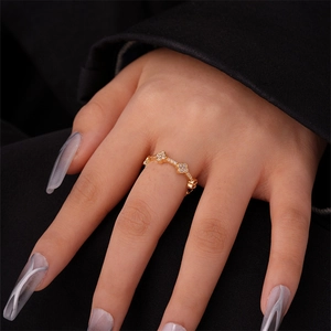Detailed view of gold clover ring with pavé-set crystals on elegant dark fabric
