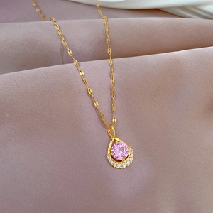 Detailed view of teardrop pendant with pink gemstone on pink silk background