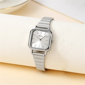Close-up of square silver watch with a metallic link strap on a textured white prop