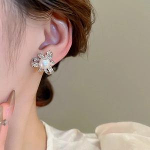Close-up of pearl flower stud earring with zircon petals on model's ear detail