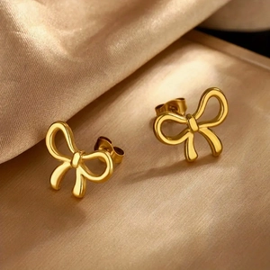 Macro shot of gold bow knot stud earrings on a silky background with elegant metallic luster