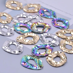 Irregular DIY jewelry pendants in gold, silver, and rainbow finishes on grey background