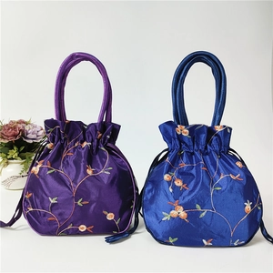 Close-up of silk drawstring bucket bags with floral vine embroidery in purple and blue