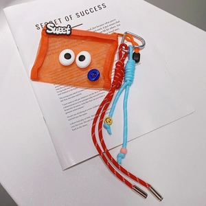 Détail d'une pochette en filet orange avec cordon tressé rouge et bleu et écusson sweet