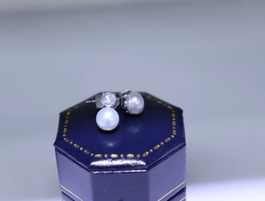 Macro shot of round pearl stud earrings with zircon in a premium blue jewelry box