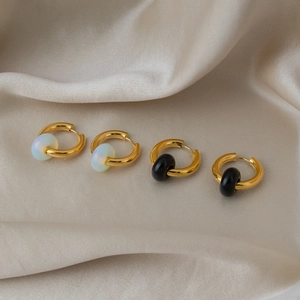 Golden stainless steel hoop earrings with natural black and white stone beads on silk fabric