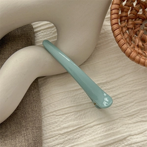 Detail shot of a minimalist Morandi blue hair clip on a decorative white sculpture