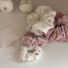 Detail of velvet scrunchies in white and lavender with elegant gold metal buckles