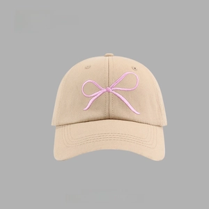 Close-up of pink bow embroidery detail on a khaki cotton baseball cap texture