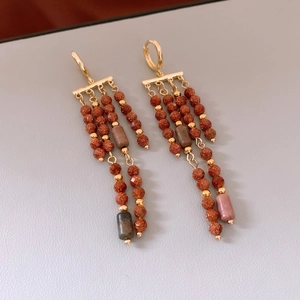 Détail de boucles d'oreilles vintage avec glands or mat, perles de grès et fini métallique