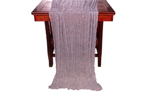 Detail of purple wrinkled cheesecloth table runner draped on a dark wooden table