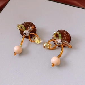 Details von handgefertigten Boho-Ohrringen mit Holzbasis, Kristallperlen und orangefarbenen Perlen