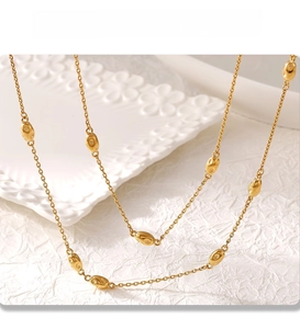 Detail of gold double-layer necklace showing the PVD electroplated finish and bead texture