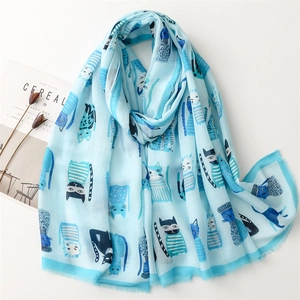 Light blue silk scarf with cute cartoon cat prints, displayed with lifestyle props