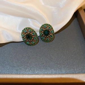 Close-up of vintage oval emerald earrings with sparkling green crystals on white silk