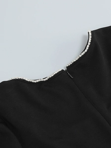 Detail of square neckline with rhinestones and invisible zipper on black evening dress