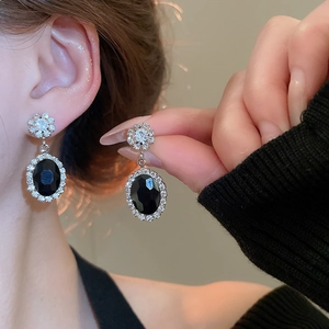 Close-up of vintage oval black gemstone earrings with sparkling crystal accents
