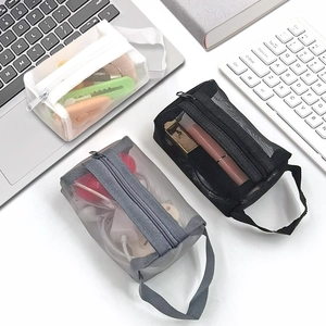 Close-up of three mesh cosmetic bags in white, gray, and black on a modern desk setup