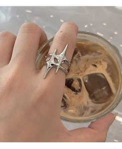 Detail of silver liquid metal star ring on model hand next to an iced coffee cup