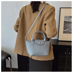 Detail of light blue woven texture and smooth leather flap on crossbody dumpling bag