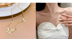 Detail of gold butterfly necklace with white opal stones and zircon stones on model