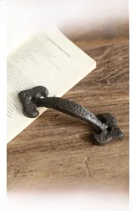 Detail shot of vintage cast iron door handle with industrial texture on rustic wood