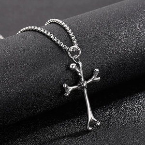 Macro view of silver cross pendant made of bone shapes with polished box chain