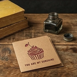 Vintage kraft paper cupcake greeting card with You Are My Sunshine print on wooden table