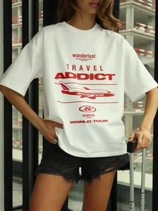 Dettaglio di una maglietta oversize in cotone bianco con stampa rossa wanderlust e aereo