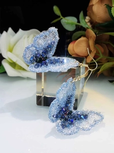 Detailed view of handmade crystal butterfly earrings with blue gradient beads and gold hooks