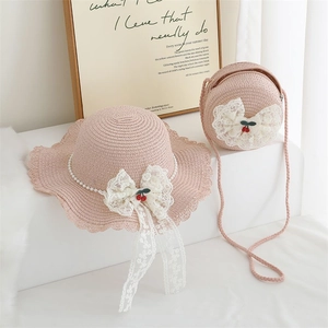 Close-up of pink straw hat and matching bag with lace bows, pearls and cherry details