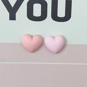 Detail of matte macaron heart resin accessories in pink colors for DIY craft projects