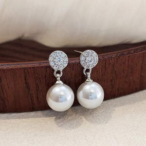 Macro shot of vintage pearl drop earrings with zircon studs on a wooden display