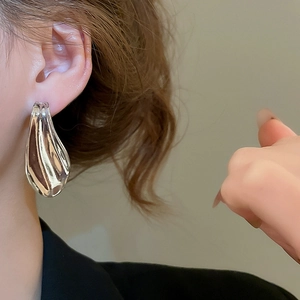 Close-up of silver wavy teardrop earrings with high-polish liquid metal texture on ear