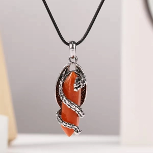 Détail d'un dragon argenté s'enroulant autour d'un pendentif en pierre orange hexagonale