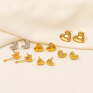 Macro shot of 304 stainless steel heart-shaped studs in gold and silver on soft beige fabric
