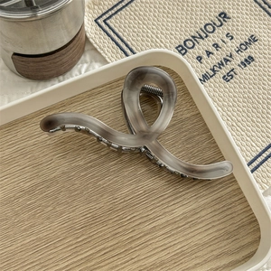 Macro shot of smoky grey translucent hair claw with matte texture on wooden tray