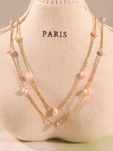 Detail of layered gold chain necklace featuring colorful natural baroque pearls on display