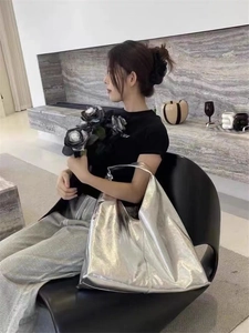 Grand sac cabas argenté avec finition métallique porté à l'épaule dans un décor moderne