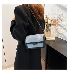 Model view of denim blue crossbody bag with black leather trim and shoulder strap