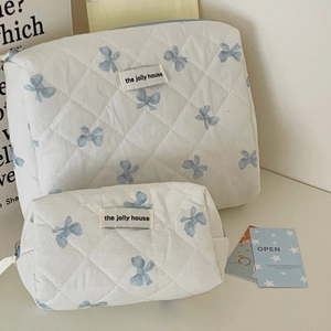 Beauty case trapuntati con fiocchi blu ed etichette su una superficie bianca pulita