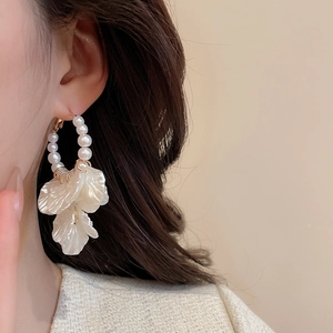 Detail of floral pearl hoop earring with gold accents on model in a soft lighting