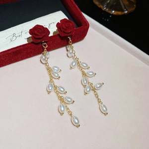 Detail of red flocked rose earrings with gold chain tassels and white oval faux pearls