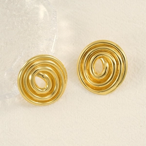 Dettaglio di orecchini a spirale dorati con finitura a specchio su tessuto beige