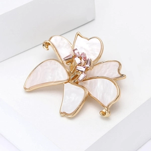 Detailed close-up of lily brooch with gold trim and pink gemstone center