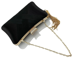 Detail of black woven fabric evening clutch with gold fringe and rhinestone buckle