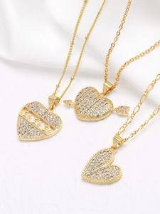 Detailed macro of gold-plated necklaces featuring zircon heart and star pendants on silk