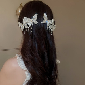 Detail view of silver butterfly hair clip with shimmering rhinestones and tassels on hair