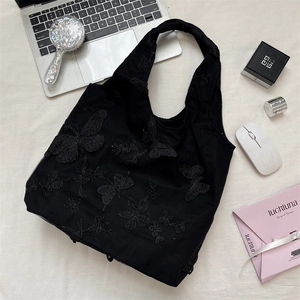 Detailed close-up of intricate butterfly embroidery on black lace sheer tote bag surface