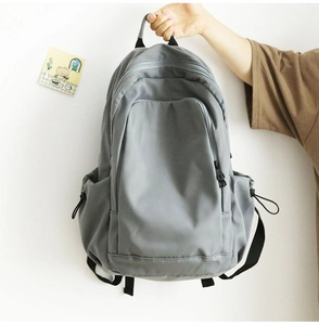 Detail view of large capacity gray backpack featuring reinforced handle and drawstring side pockets